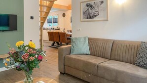 A living room with a sofa, a coffee table with a vase of flowers, a staircase, a dining area with chairs, and a kitchen in the background. - Gorgeous home in Marienberg with WiFi (Marienberg)