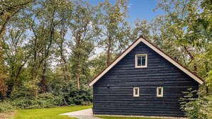 A dark wooden cabin with a triangular roof, surrounded by lush greenery and a clear sky. - Gorgeous home in Marienberg with WiFi (Marienberg)