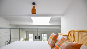 Una camera da letto moderna con un letto grande, una testata in legno, un lucernario e vista su un balcone e una porta.
