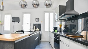 Una cucina moderna con isola centrale, elettrodomestici in acciaio inossidabile e luci a sospensione.