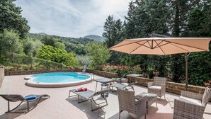 A pool area with lounge chairs, a table, and an umbrella.