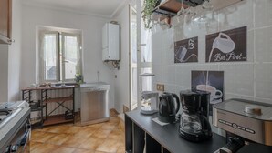 A modern kitchen with a dishwasher, coffee maker, and kettle on the counter.