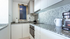 A compact kitchen with white cabinets, a granite countertop, a window, and a coffee maker. - Cozy apartment in Torrevieja (Torrevieja)
