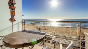 A balcony with a view of the beach, a round wicker table, and a colorful umbrella. - Cozy apartment in Torrevieja (Torrevieja)