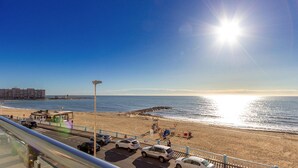 A beach view with a clear sky, a parking area, and a building in the background. - Cozy apartment in Torrevieja (Torrevieja)
