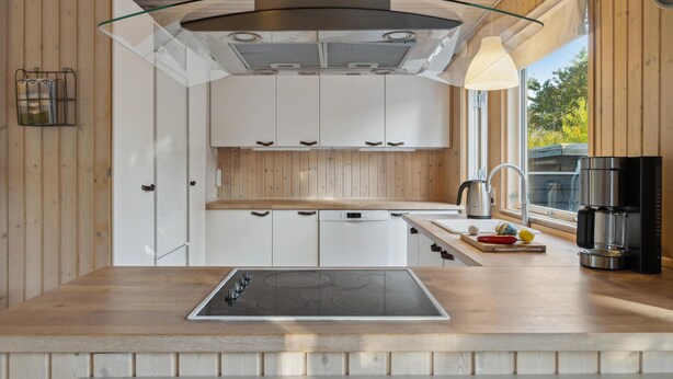 A modern kitchen with white cabinets, a stainless steel range hood, a glass pendant light, and a coffee machine. - Amazing home in Nykøbing Sj with WiFi (Nykøbing Sj)