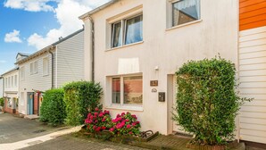 Une rangée de maisons de ville avec une allée pavée, un petit jardin agrémenté de fleurs roses et une boîte aux lettres sur le mur avant.