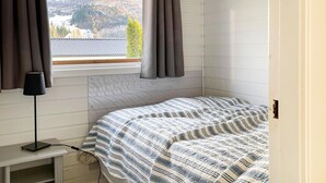 Une chambre à coucher avec un lit, une table de chevet, une lampe et une fenêtre avec des rideaux.