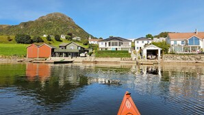 Un village au bord d’un lac, avec des maisons, un quai et une montagne en arrière-plan.