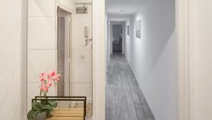 Un pasillo con una orquídea en maceta, un interruptor de luz y una puerta que da a una habitación.