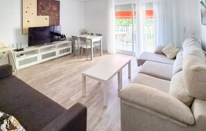 A modern living room with a sofa, a coffee table, a TV, and a dining area with chairs and a table.