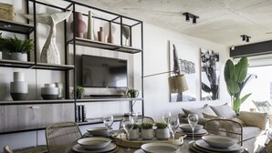 A dining area with a round table set for six, surrounded by wicker chairs. A large plant is visible in the background. - Departamento B Vista Privilegiada Cerro Barón (Valparaíso)