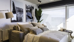 A modern bedroom with a large bed, a plant, and artwork on the wall. - Departamento B Vista Privilegiada Cerro Barón (Valparaíso)