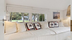 A white, wooden bench with quilted pillows and a star-patterned pillow.
