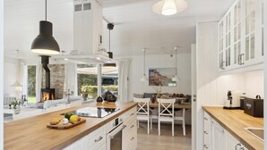 A modern kitchen with white cabinetry, a central island with a wooden countertop, and a built-in stove.