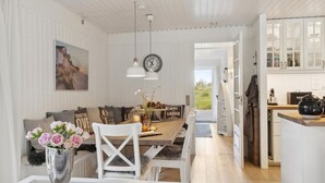 A dining area with a wooden table, white chairs, a vase of flowers, and a clock on the wall.