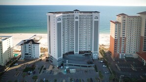 Ein Hochhaus-Hotel mit mehreren Etagen, einem Parkplatz und Blick auf den Strand.