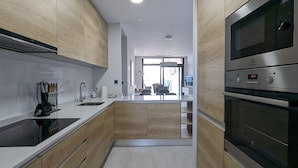 A modern kitchen with wooden cabinets, stainless steel appliances, and a central island. - SUNSET WAVES WoW apartment (Benidorm)