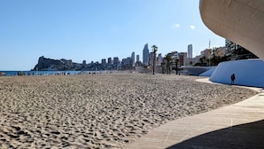 A beach with a city skyline in the background, a wooden boardwalk, and palm trees. - SUNSET WAVES WoW apartment (Benidorm)