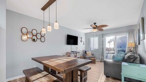 Una sala moderna con una mesa de comedor de madera, bancos, un sofá y una mesita auxiliar color turquesa.