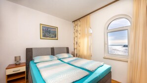 A bedroom with a bed, a nightstand, a lamp, a window with a view, and a painting on the wall. - Stunning apartment in Okrug Gornji with WiFi (Okrug Gornji)