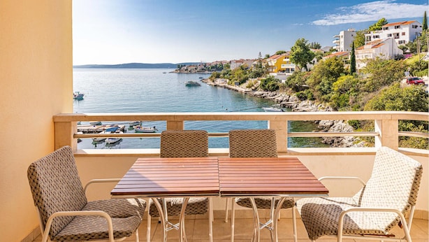 A balcony with a table and chairs overlooking a coastal town. - Stunning apartment in Okrug Gornji with WiFi (Okrug Gornji)