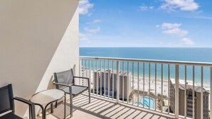 Ein Balkon mit zwei Stühlen und Blick auf Strand und Meer.