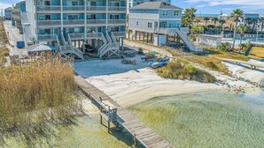 Un hotel frente a la playa con varios balcones, un paseo marítimo y aguas cristalinas.
