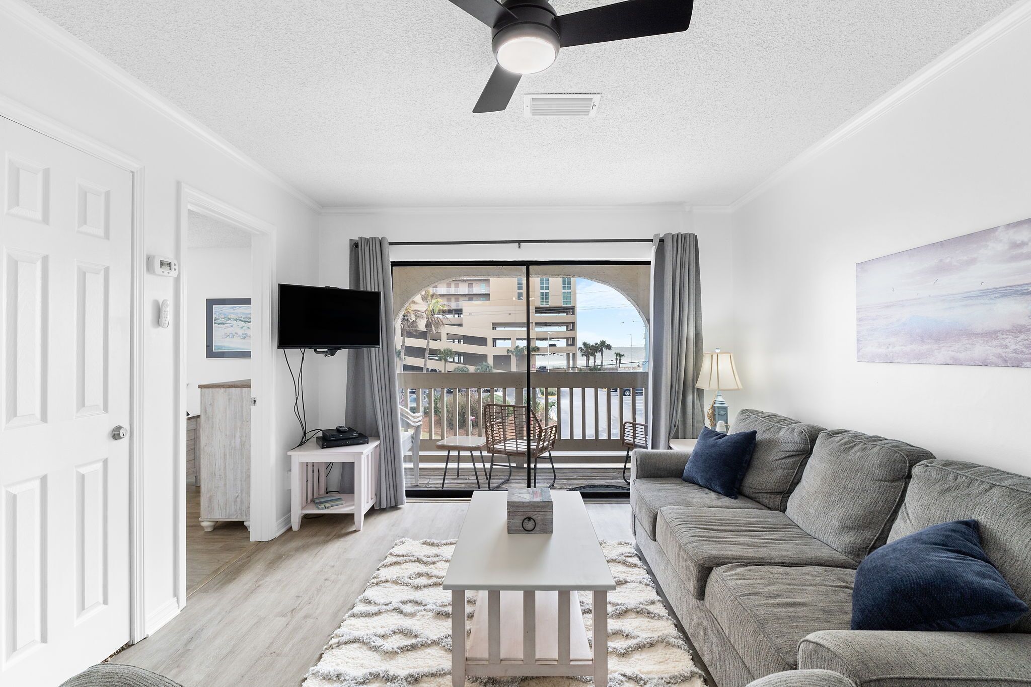 A modern living room with a grey sofa, a white coffee table, and a ceiling fan.