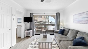 A modern living room with a grey sofa, a white coffee table, and a ceiling fan.