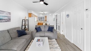A modern living room with a grey sectional sofa, a white coffee table, and a ceiling fan.