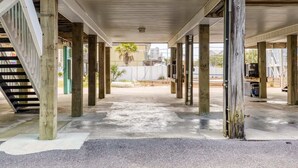 Un espacio al aire libre cubierto con una escalera a la izquierda, pilares de madera y suelo de concreto.