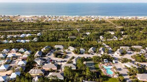 A resort with multiple bungalow-style buildings, a central pool area, and a view of the ocean. - 🌞Beach Cottage in Ft Morgan-Pool-The Rookery 2202🌞 (Gulf Shores)