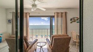 Ein Balkon mit Blick auf den Strand, ein Deckenventilator und ein Tisch mit Stühlen.
