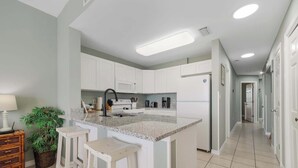 A kitchen with white cabinets, a granite countertop, and a central island with stools.