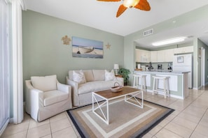 A living room with a sofa, coffee table, and a kitchen in the background.