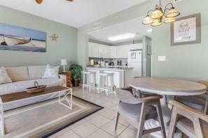 A modern living room with a sofa, coffee table, and a dining area with chairs and a table.
