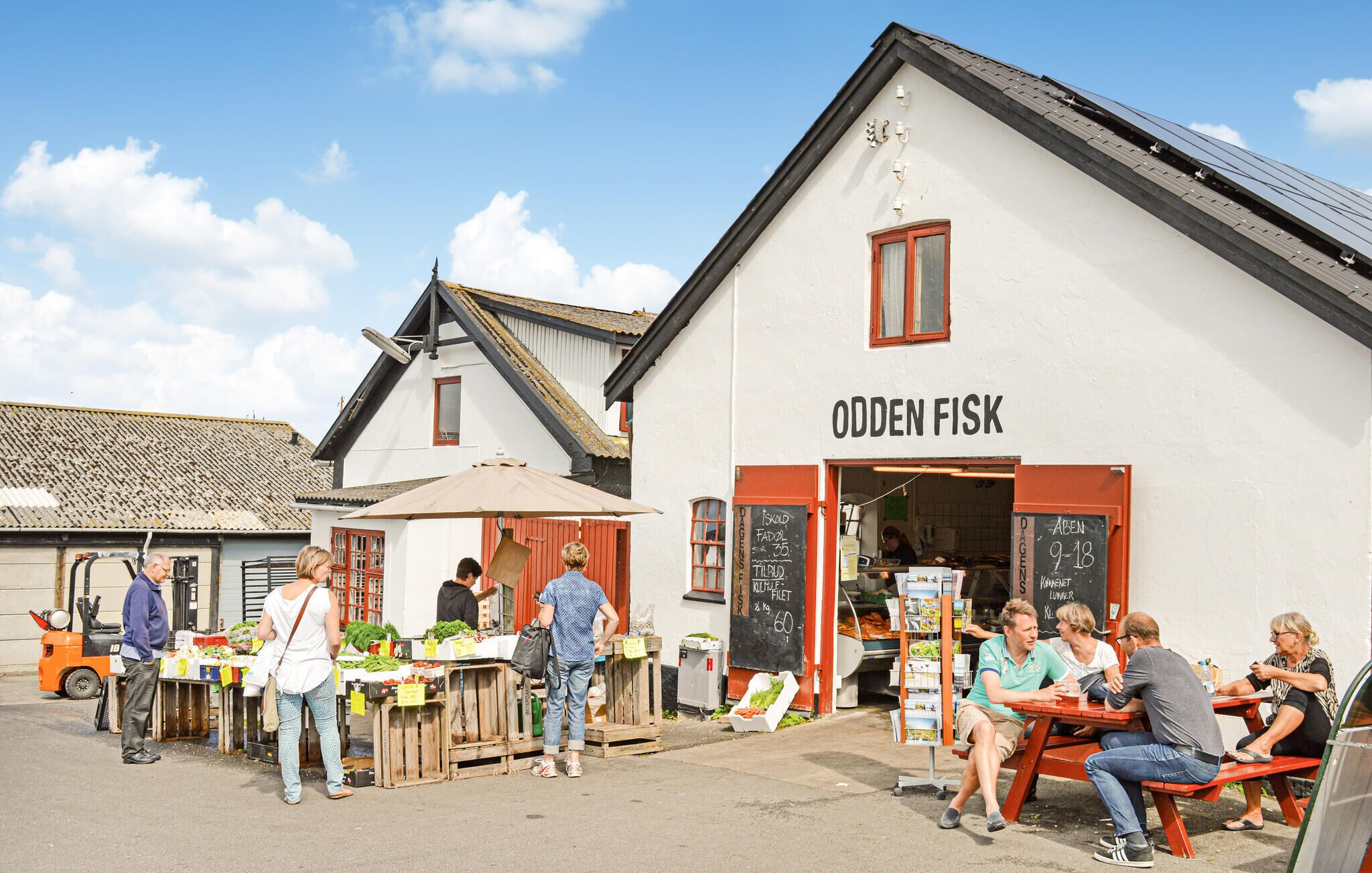 Un bâtiment sur lequel on peut lire l’inscription « ODDEN FISK », avec un étal de marché installé à l’extérieur.