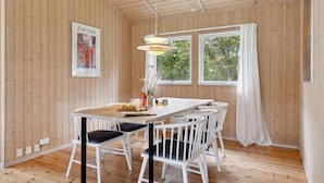 A wooden-paneled room with a white dining table, chairs, and a pendant light. - 3 bedroom lovely home in Nykøbing Sj (Nykøbing Sj)