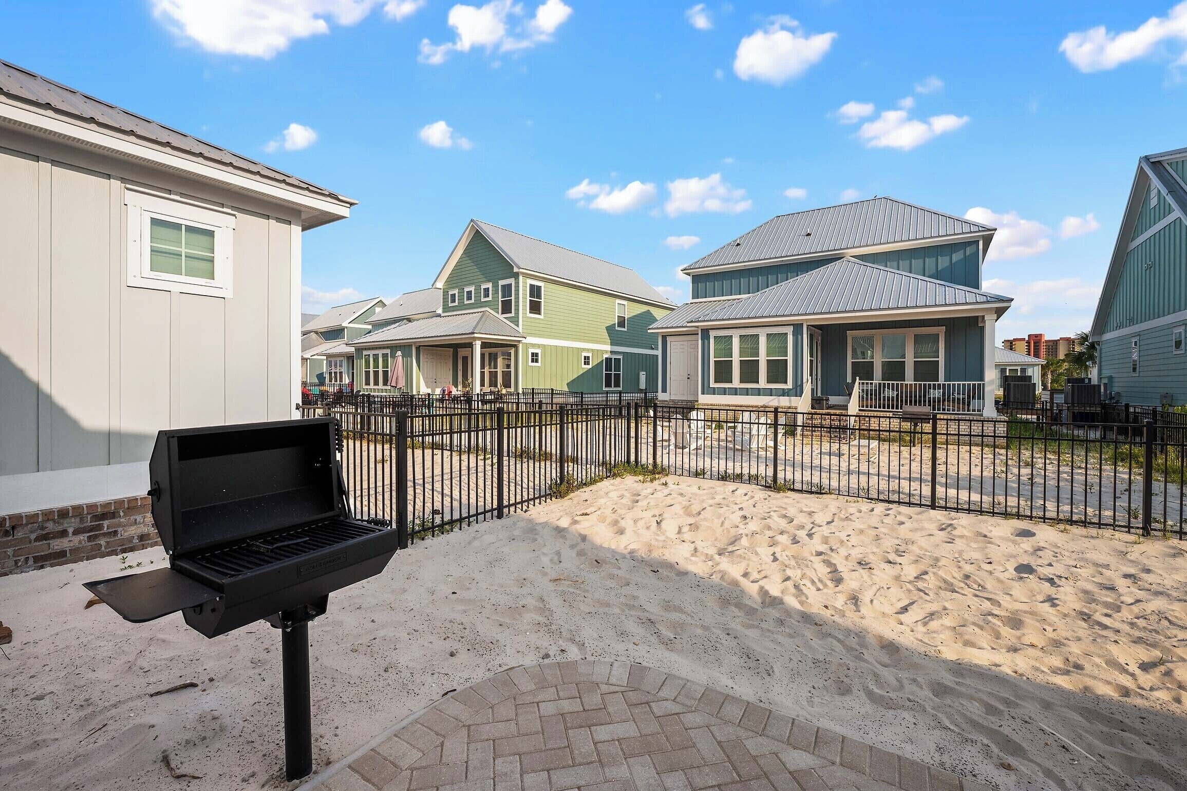 A residential area with houses, a barbecue grill, and a paved walkway.