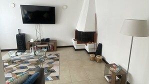 Una sala de estar con televisor de pantalla plana, chimenea, sofá, mesa de centro y lámpara.