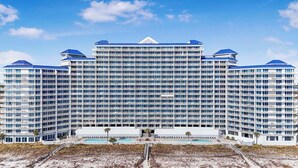 A large, multi-story hotel with a central courtyard and a swimming pool. - Views of beach w/ Two Pools-Lighthouse-918 (Gulf Shores)