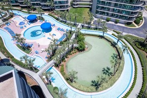 Vue aérienne d’un complexe hôtelier comprenant une grande piscine, un terrain de golf et plusieurs bâtiments.
