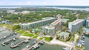 Un hotel con varias construcciones, un puerto deportivo y una playa.
