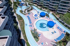Un complexe hôtelier doté de plusieurs piscines, de chaises longues et d’un grand bâtiment avec des balcons.