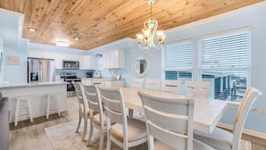 A modern kitchen with white cabinets, a central island, and a dining area with a round table and chairs.