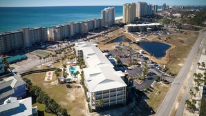 Vista aérea de un complejo hotelero costero con varios edificios de gran altura, una piscina grande y una zona de playa.