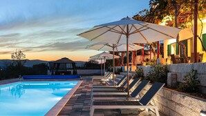 A poolside area with lounge chairs and umbrellas, a gazebo, and a view of the mountains at sunset. - Lovely home in Dicmo Prisoje (Dicmo Prisoje)