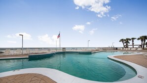A swimming pool with a curved edge, surrounded by a brick walkway and lounge chairs. - 🌊Gulf Front Condo with Amazing Views-Ocean House 2604🌊 (Gulf Shores)