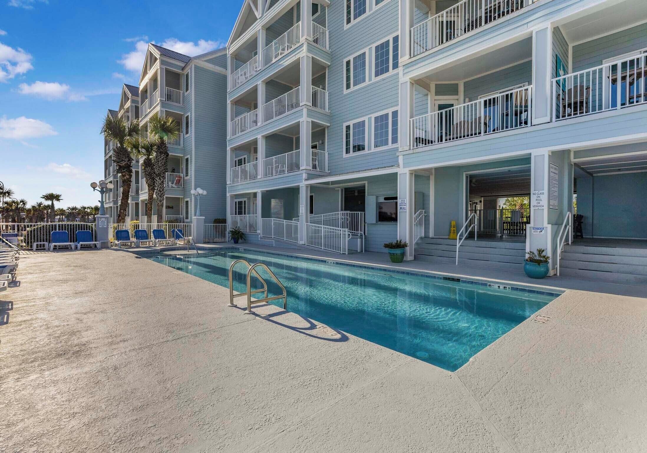 A multi-story hotel with a swimming pool, balconies, and a beach view.